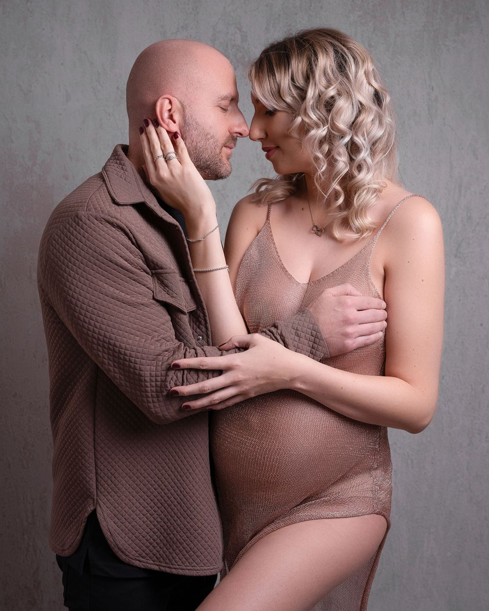 Intimate maternity portrait in soft tones against grey background.