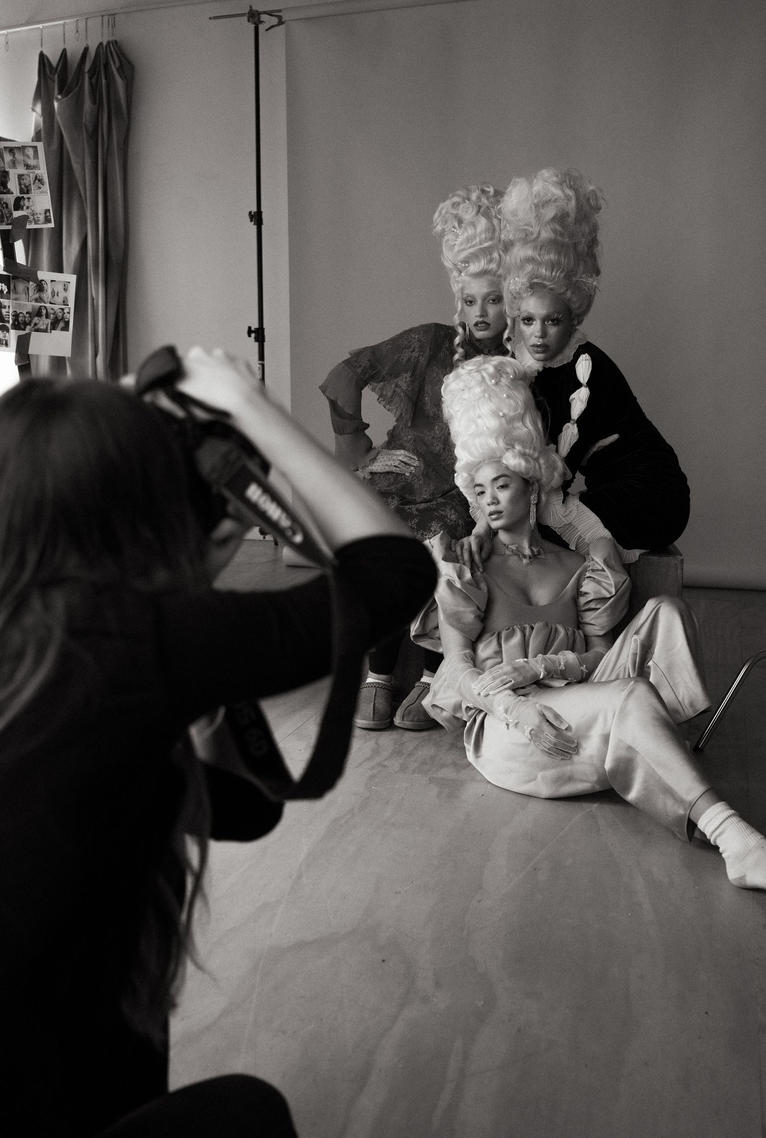 Behind the scenes photoshoot capturing models in elaborate Marie Antoinette style wigs and costumes.