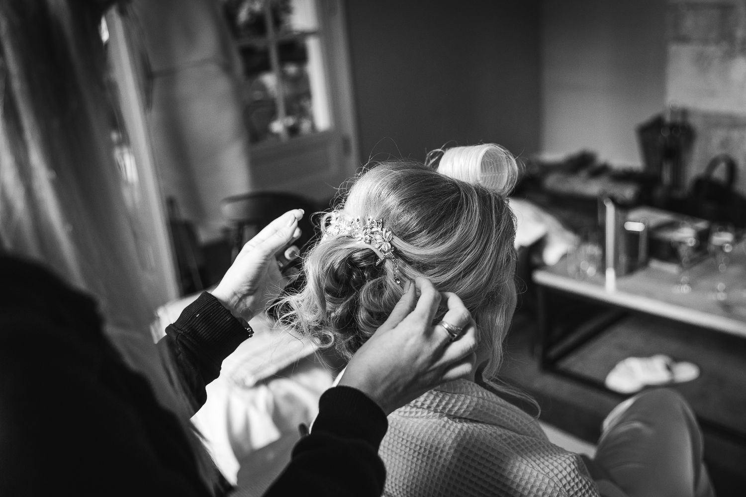 Black and white photo capturing hair styling preparation during a wedding day.