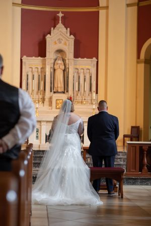 Wedding ceremony in a traditional church with ornate altar and architecture.