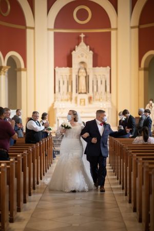 Interior of Catholic church during wedding ceremony with grand altar and wooden pews.