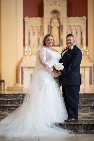 Wedding couple standing at church altar with traditional decor and candlelight.