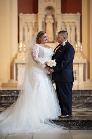 Wedding portrait in church with ornate altar and candles in background.