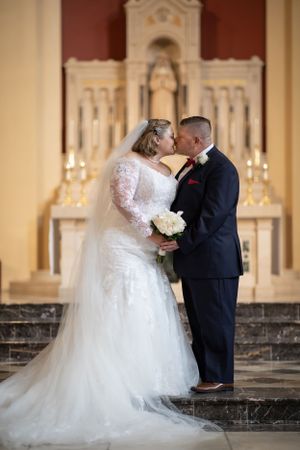 Romantic moment captured in church with ornate altar and candlelight.