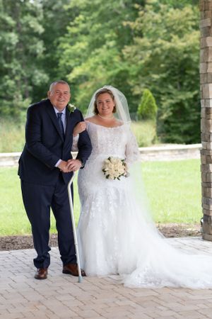 Wedding portrait on brick pathway with lush green garden backdrop.