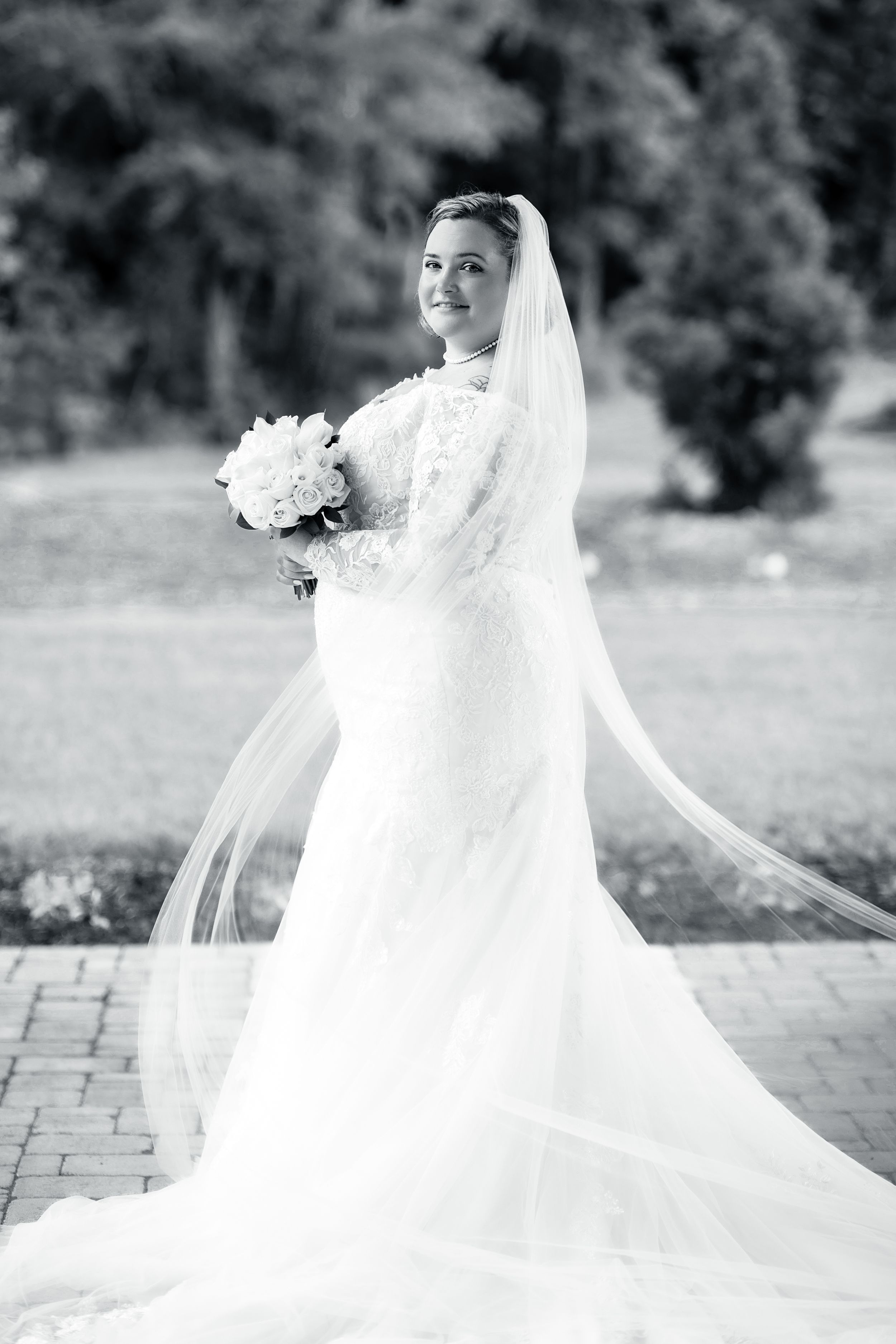 Black and white bridal portrait featuring a flowing cathedral veil and white bouquet.