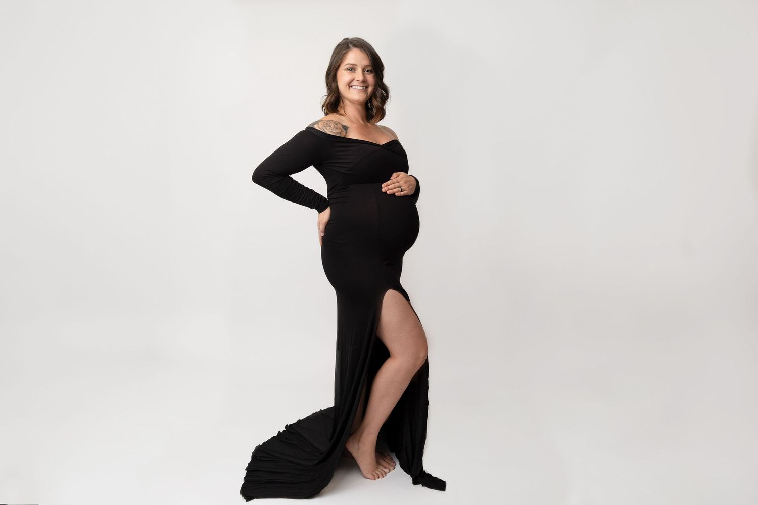 Elegant maternity portrait featuring black floor-length dress with side slit.