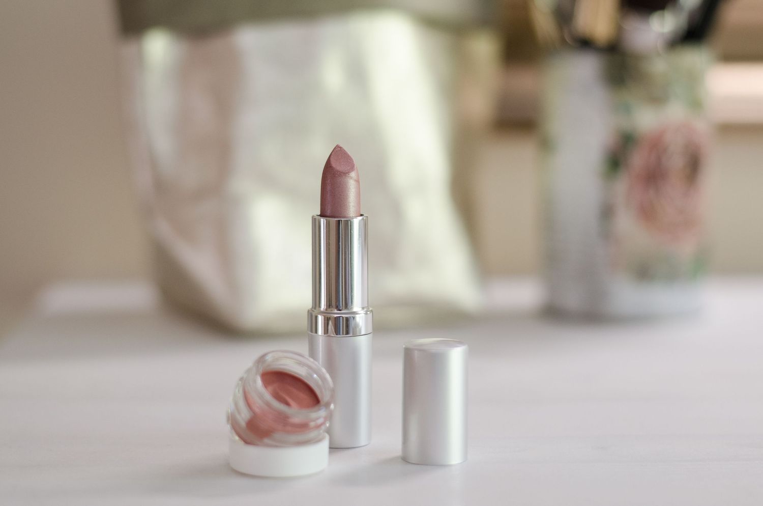Elegant display of cosmetic products and makeup tools on a white vanity counter.