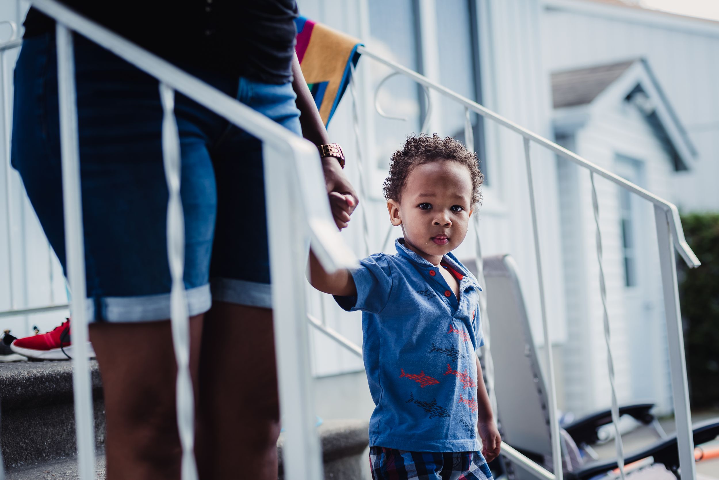 A woman and her son walk down the back steps at their house, focus on their feet.