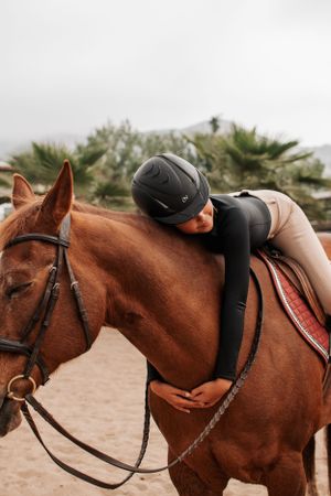 A rider demonstrates an affectionate moment with their chestnut horse during training.