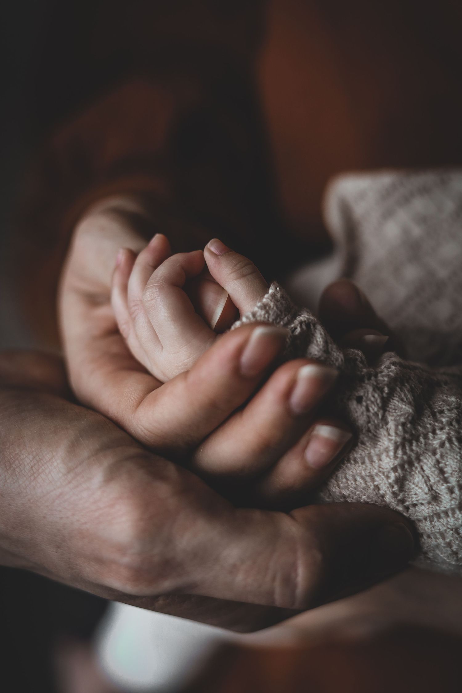 Newborn baby grasping parent's finger in a tender close-up photograph.