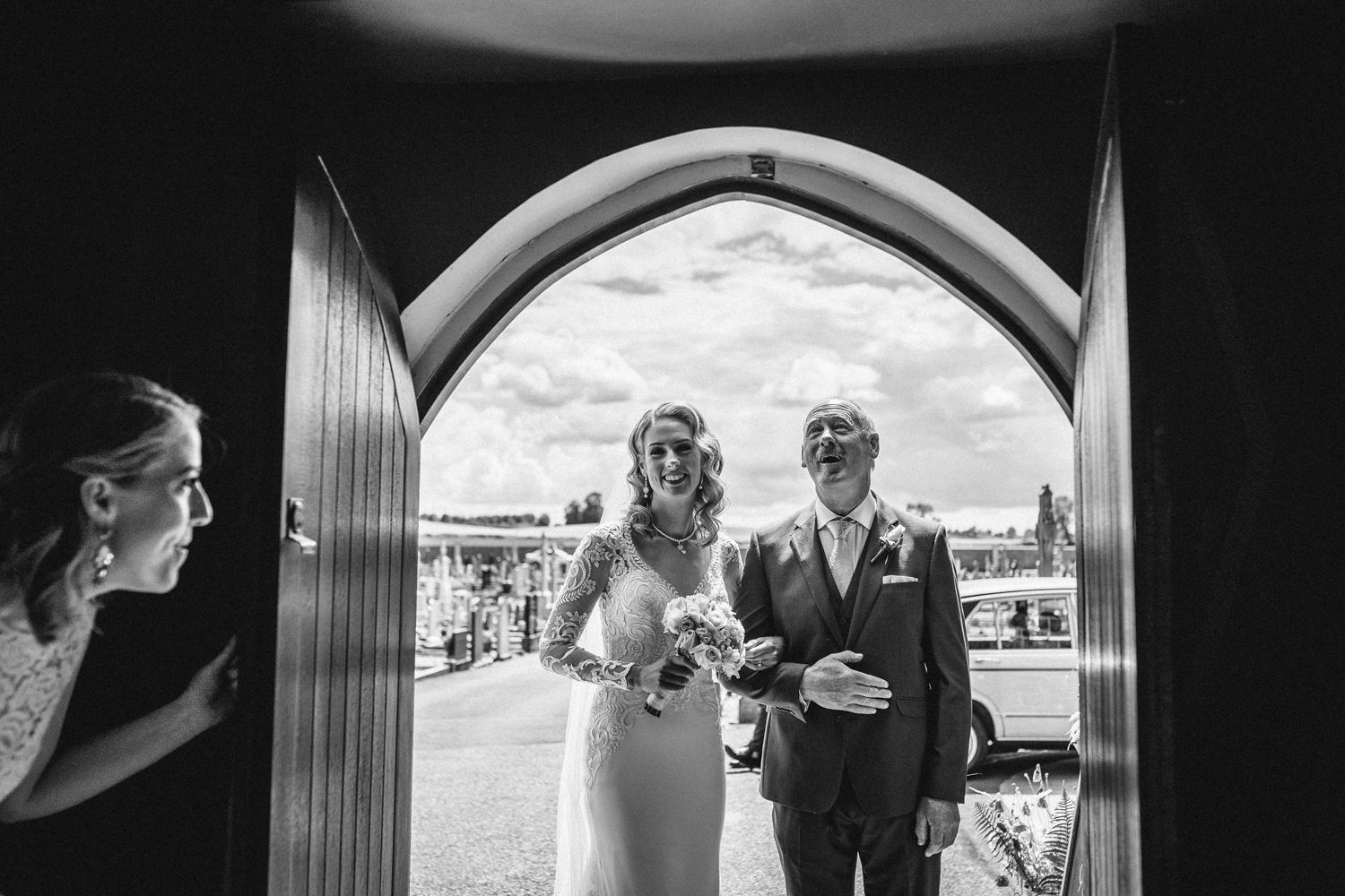 Couple emerging through grand arched doorway at their wedding ceremony.