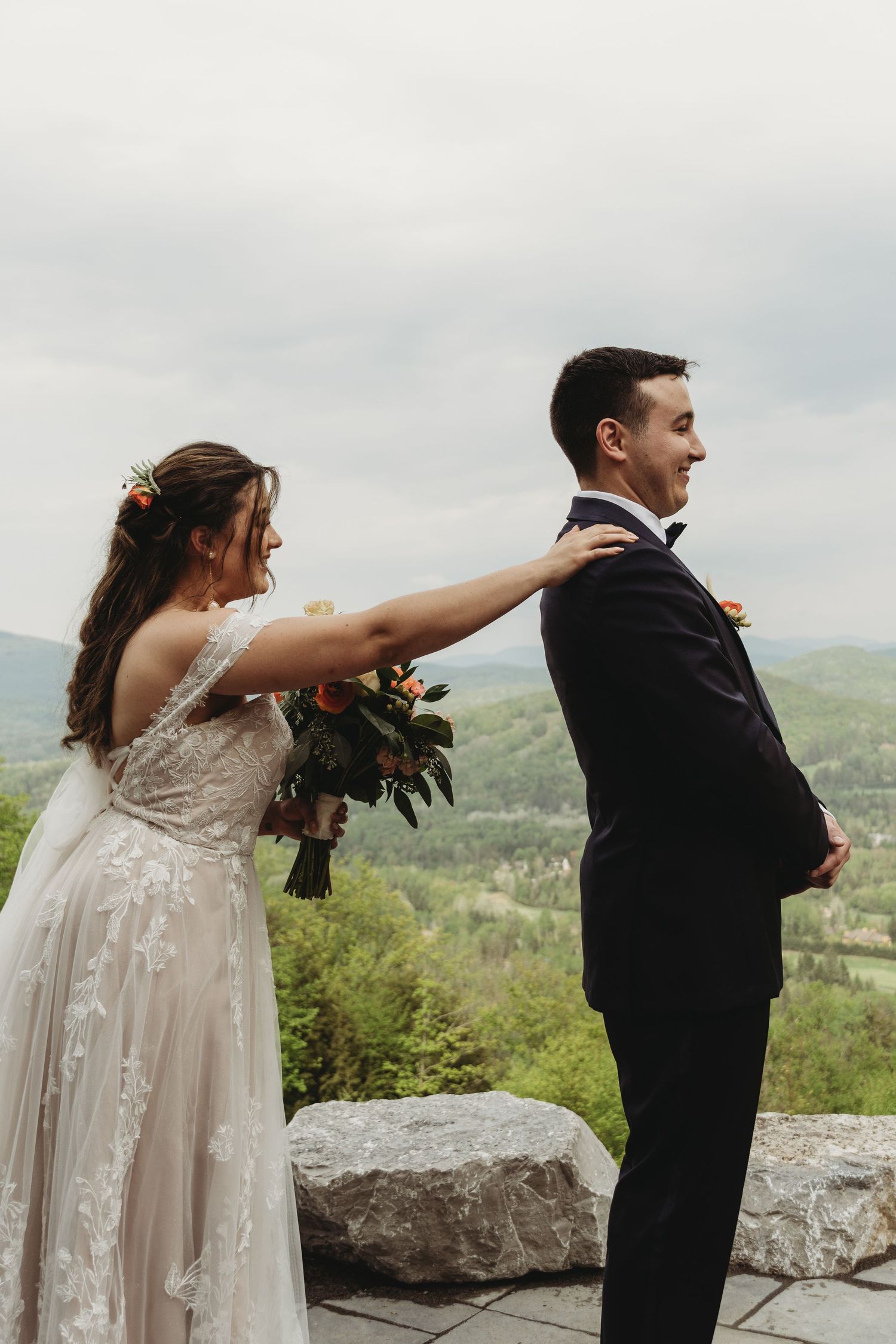 Couple in wedding attire sharing first look moment on mountain overlook.