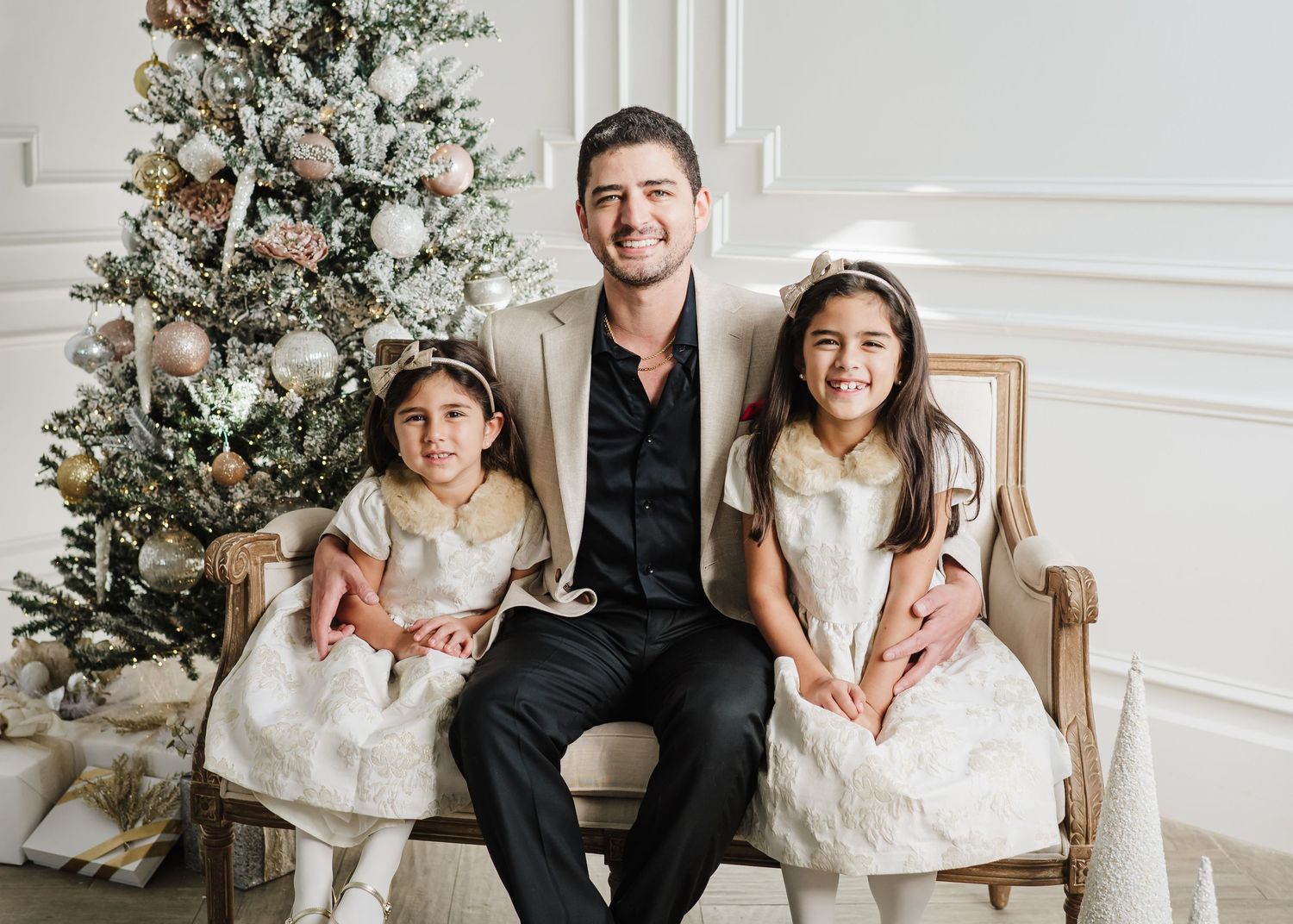 Indoor family holiday photoshoot with Christmas tree and elegant white decor.