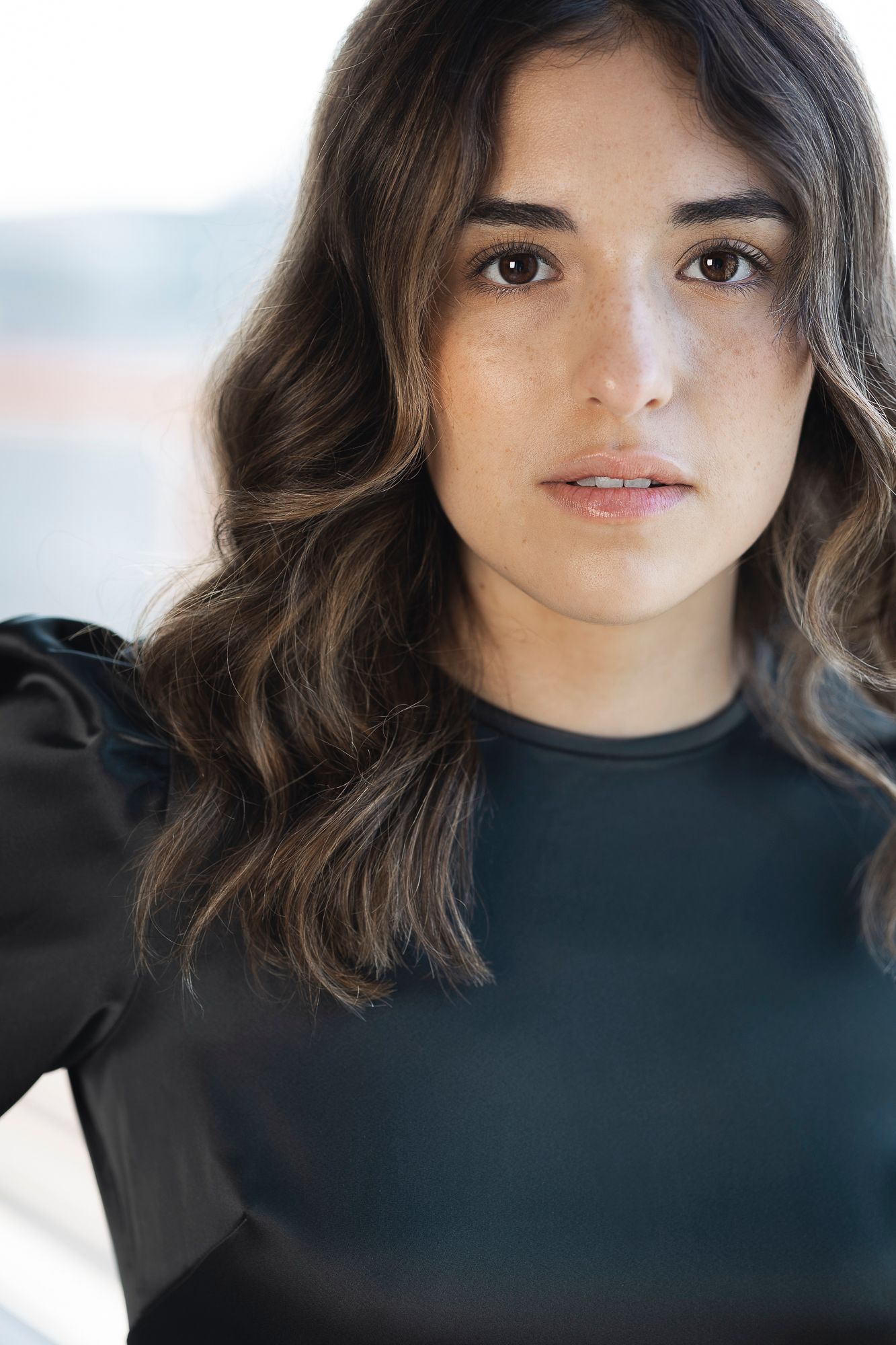 A studio headshot of a beautiful Mexican woman looking directly into camera. She is dressed in business attire.