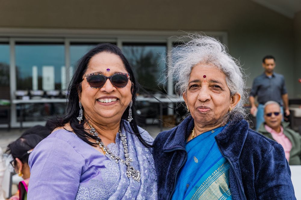 Two women in traditional Indian clothing stand together outside a building.