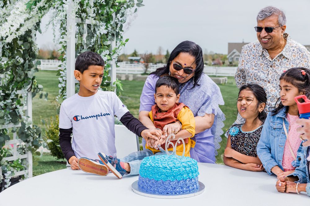 Family members gather around a blue ombre birthday cake at an outdoor celebration.