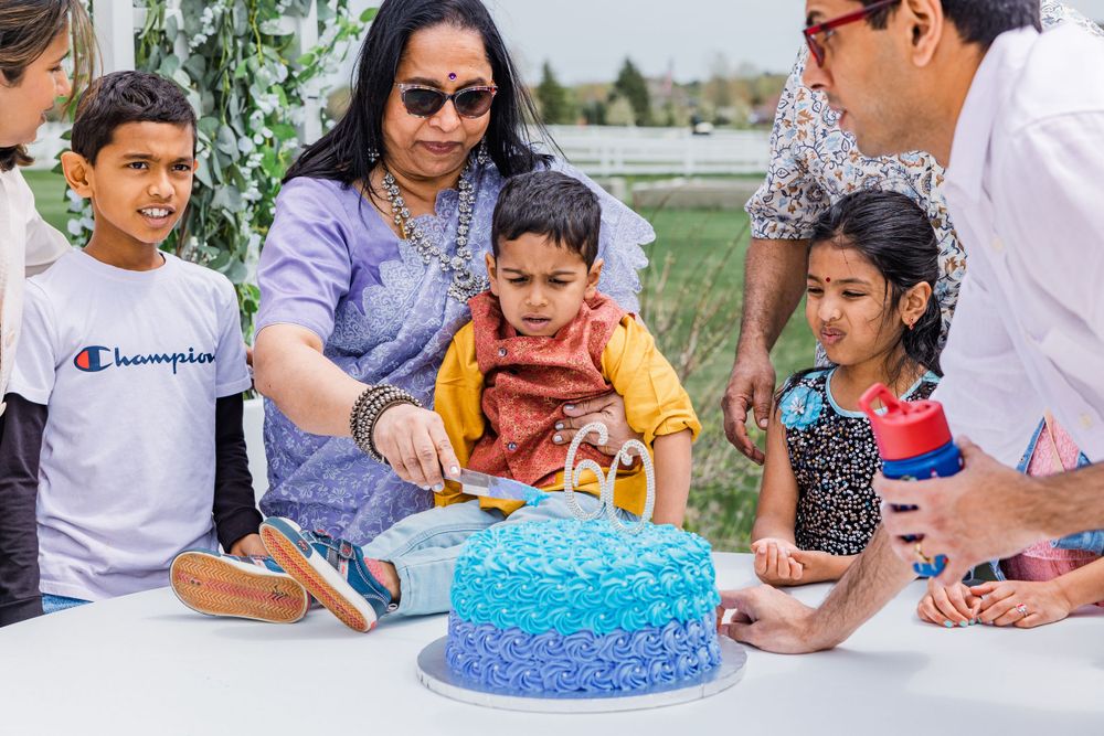People gather around a blue ombre birthday cake at an outdoor party.