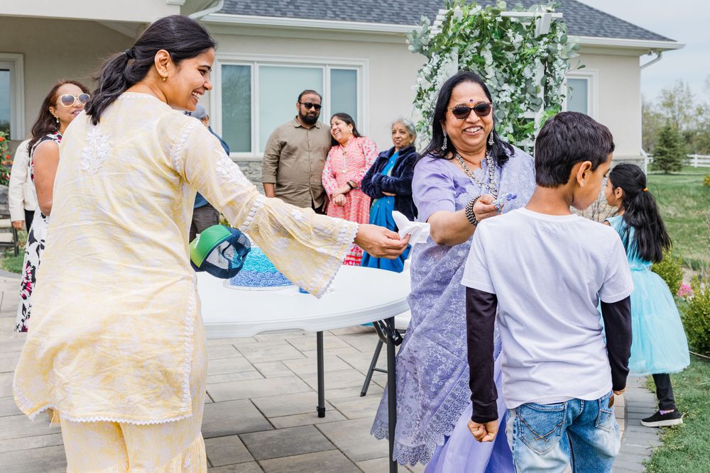 People celebrating at an outdoor party with a decorated cake on a white table.