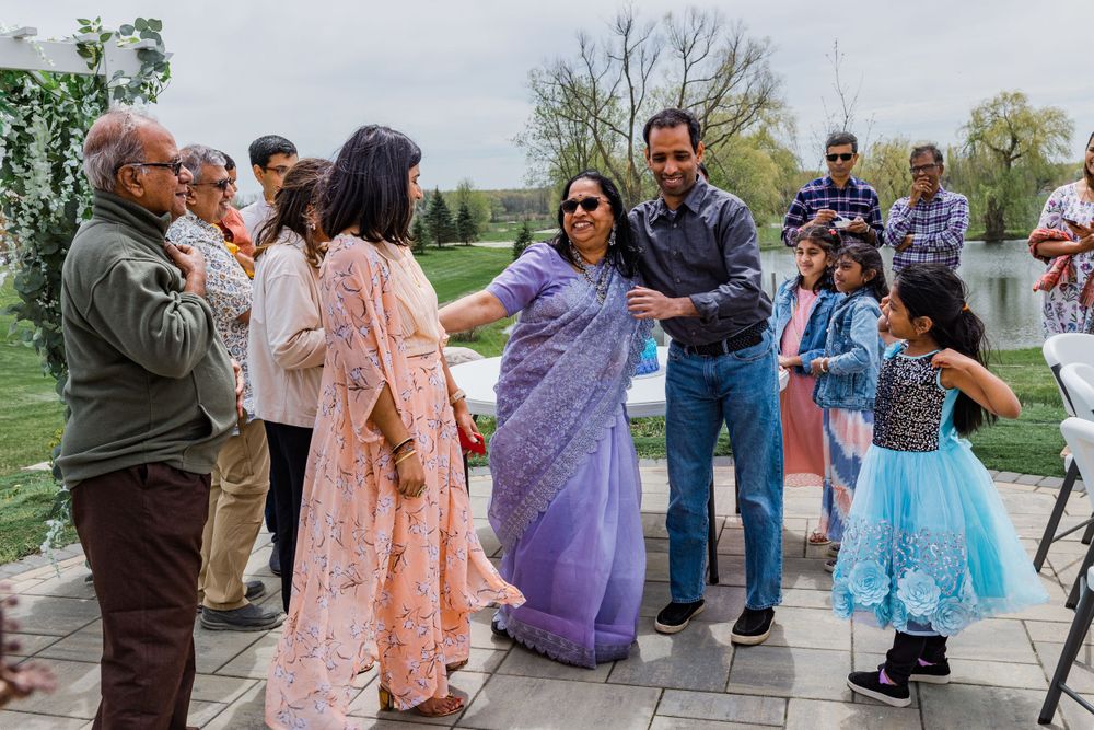A celebratory gathering outdoors with people in traditional Indian attire dancing and socializing.