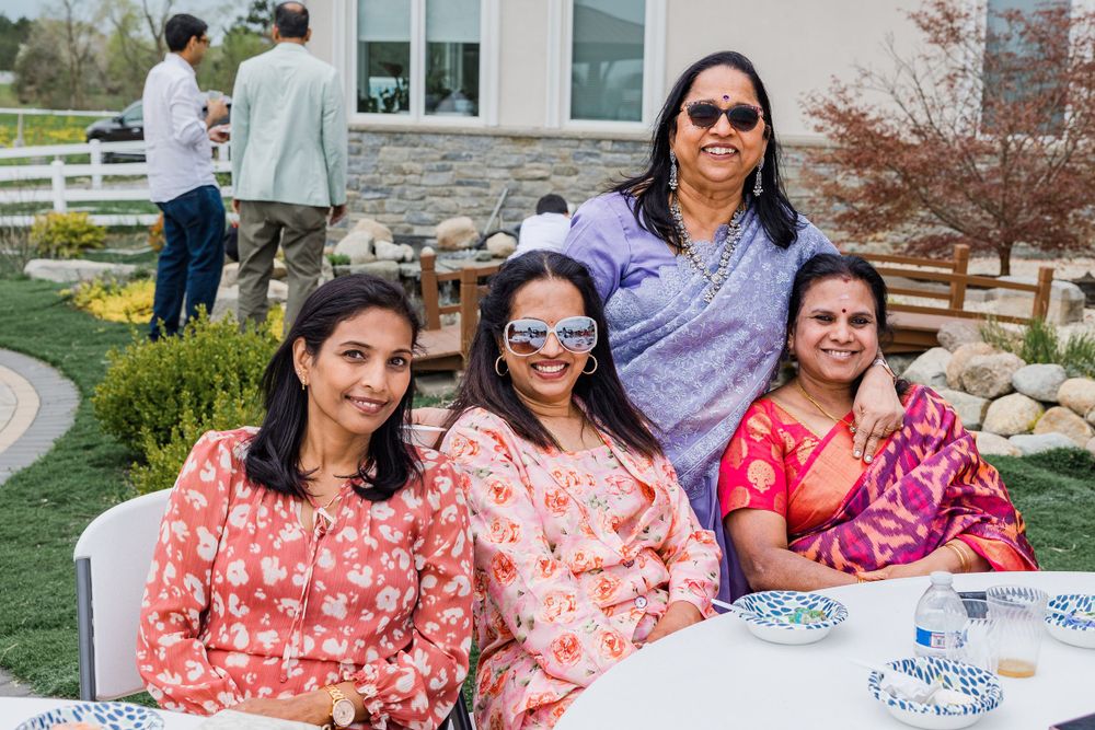 A group in traditional Indian attire sits at an outdoor table during a celebration.