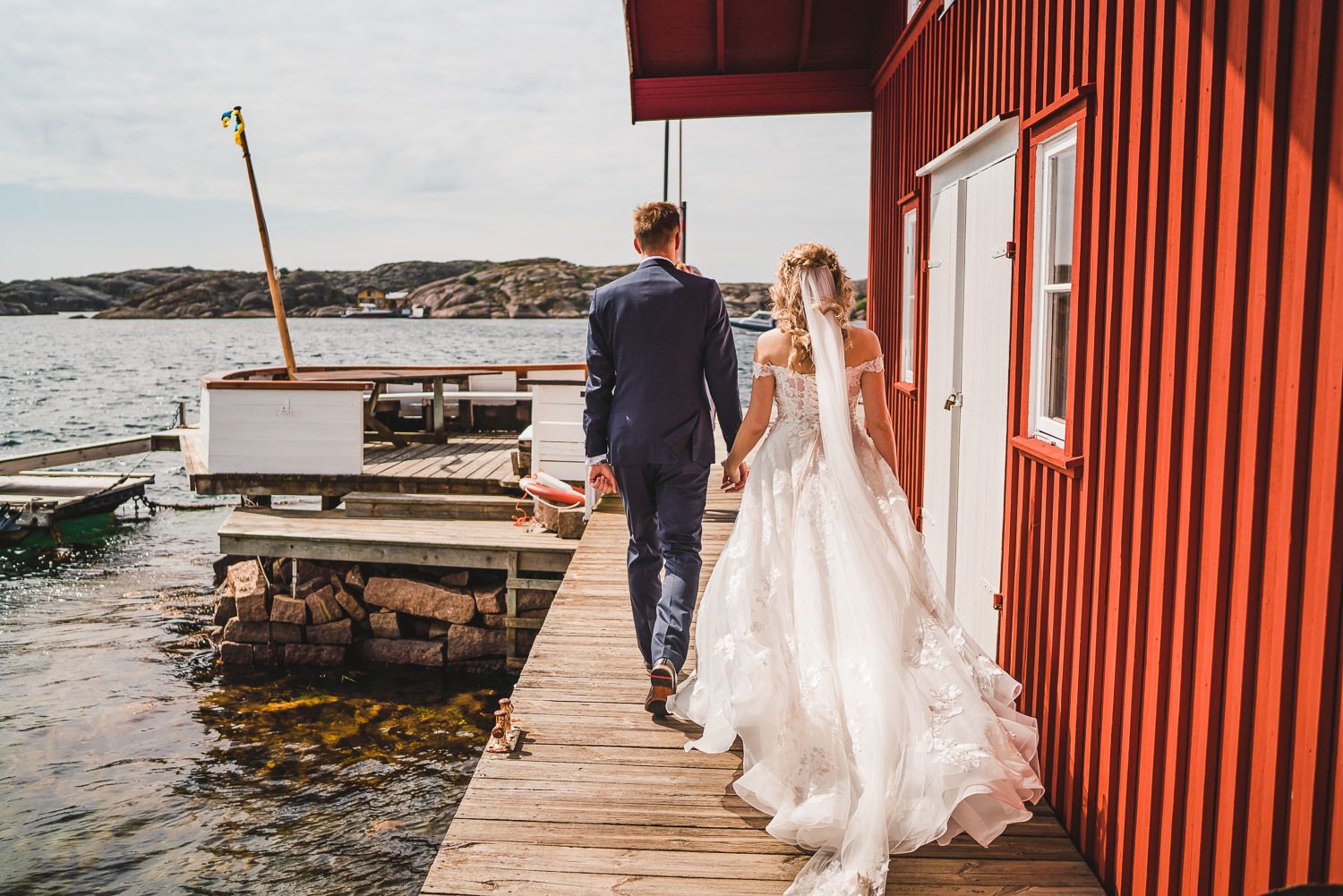 Brudpar går på bryggan förbi Sippans bu på Fisketången i Kungshamn Sotenäs en somrig dag på väg till Hållö