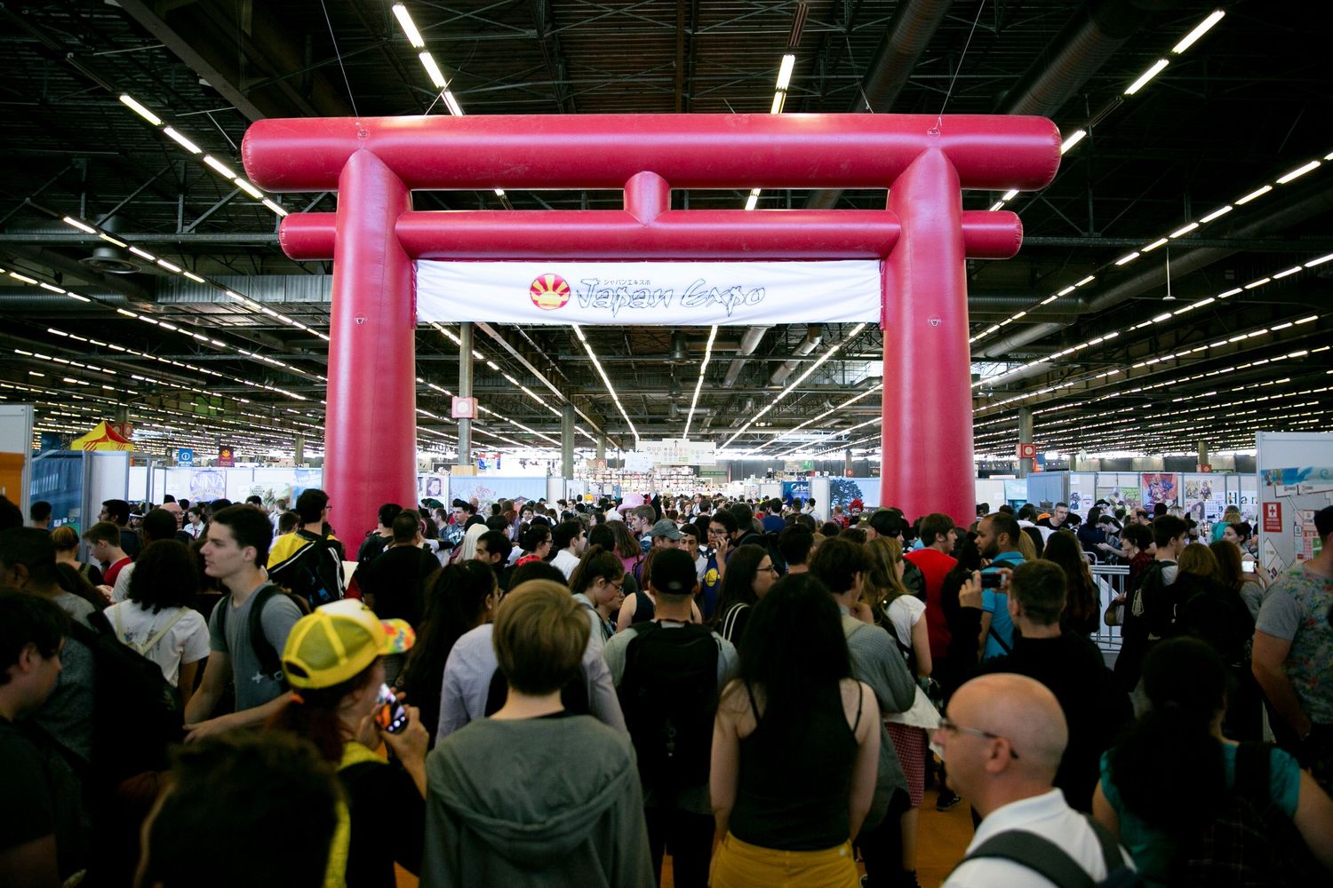 Large pink torii gate structure at a crowded indoor convention or event space.