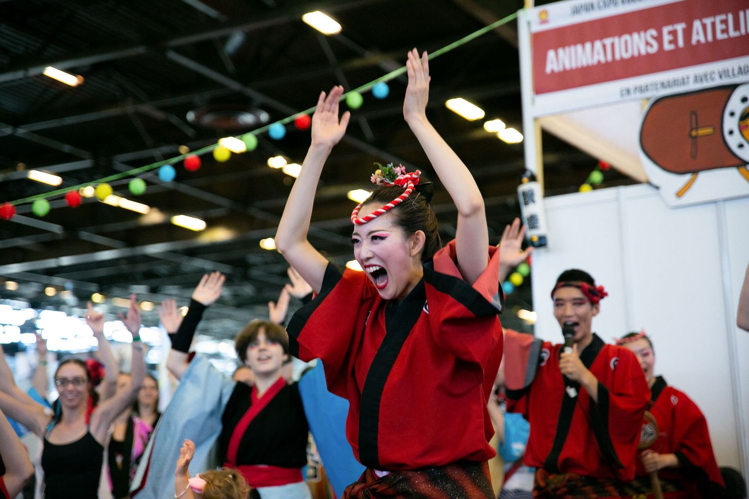 Energetic group dance performance with participants in red traditional attire.