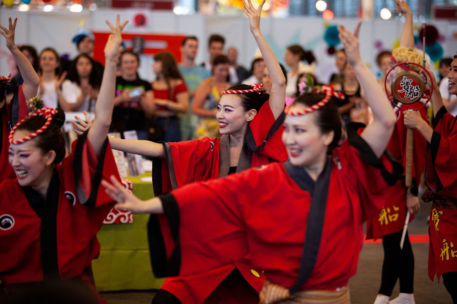 Group dancers in red traditional costumes performing synchronized movements at cultural festival.