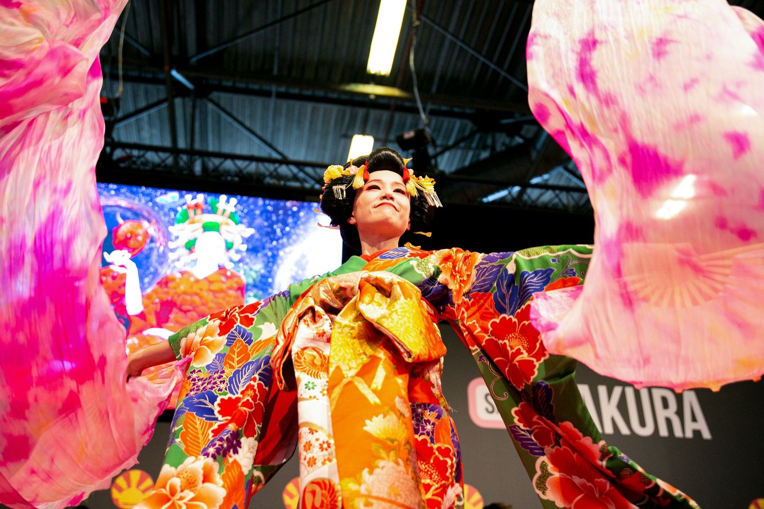 Vibrant performance with colorful pink fans and traditional Japanese festival attire.