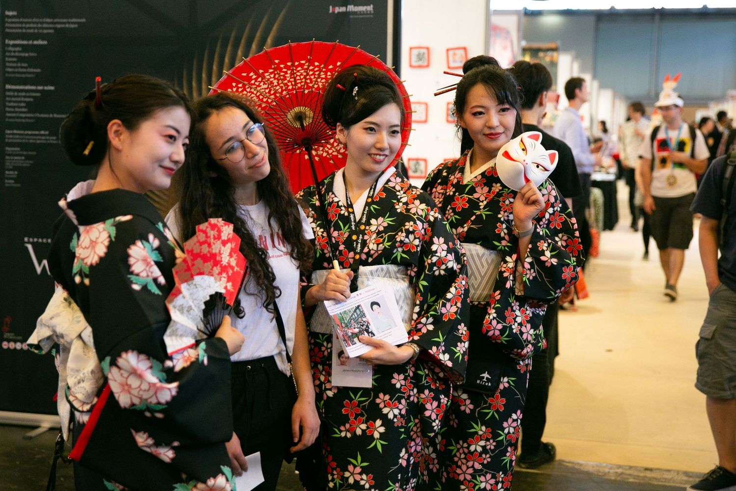 Group wearing floral patterned yukata poses together at cultural festival.