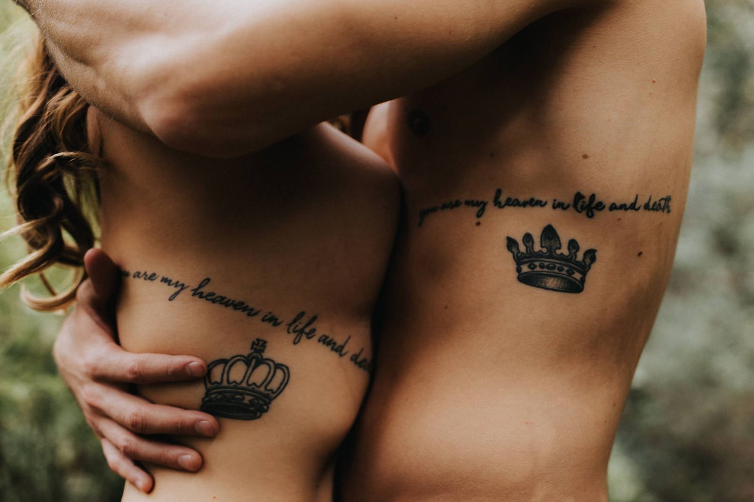 Two matching crown tattoos with script text on bare skin.