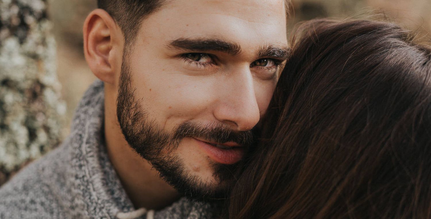 Close up portrait against tree bark in natural lighting.