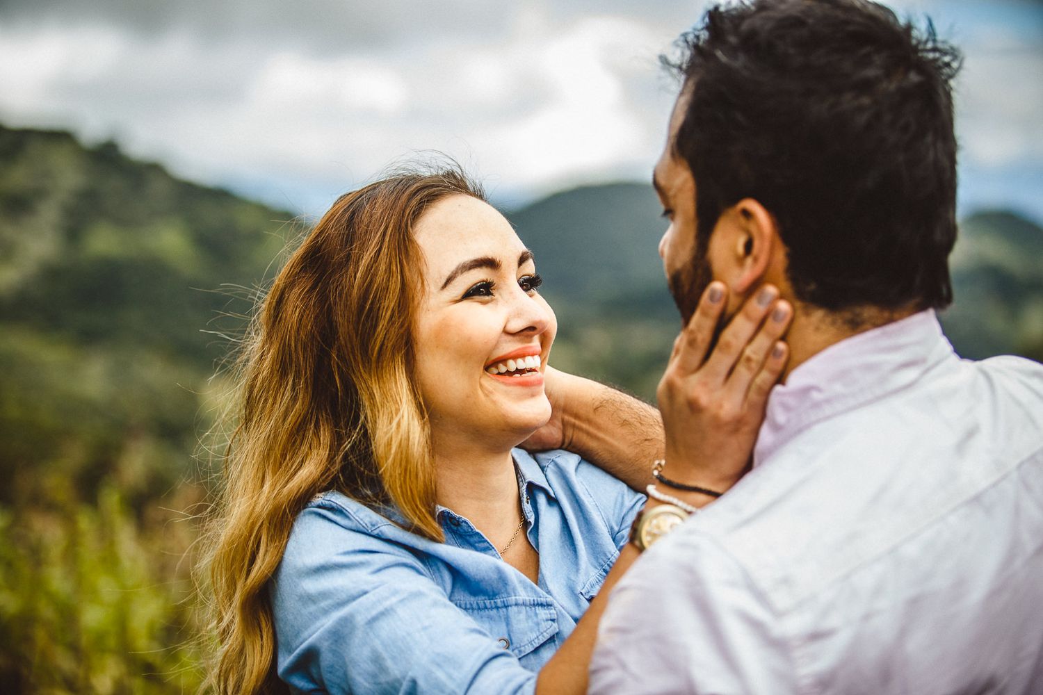 Intimate couple moment outdoors with mountain landscape in background.