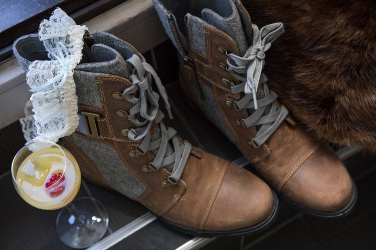 Brown leather boots with lace details and a lace bow accessory next to a champagne glass.