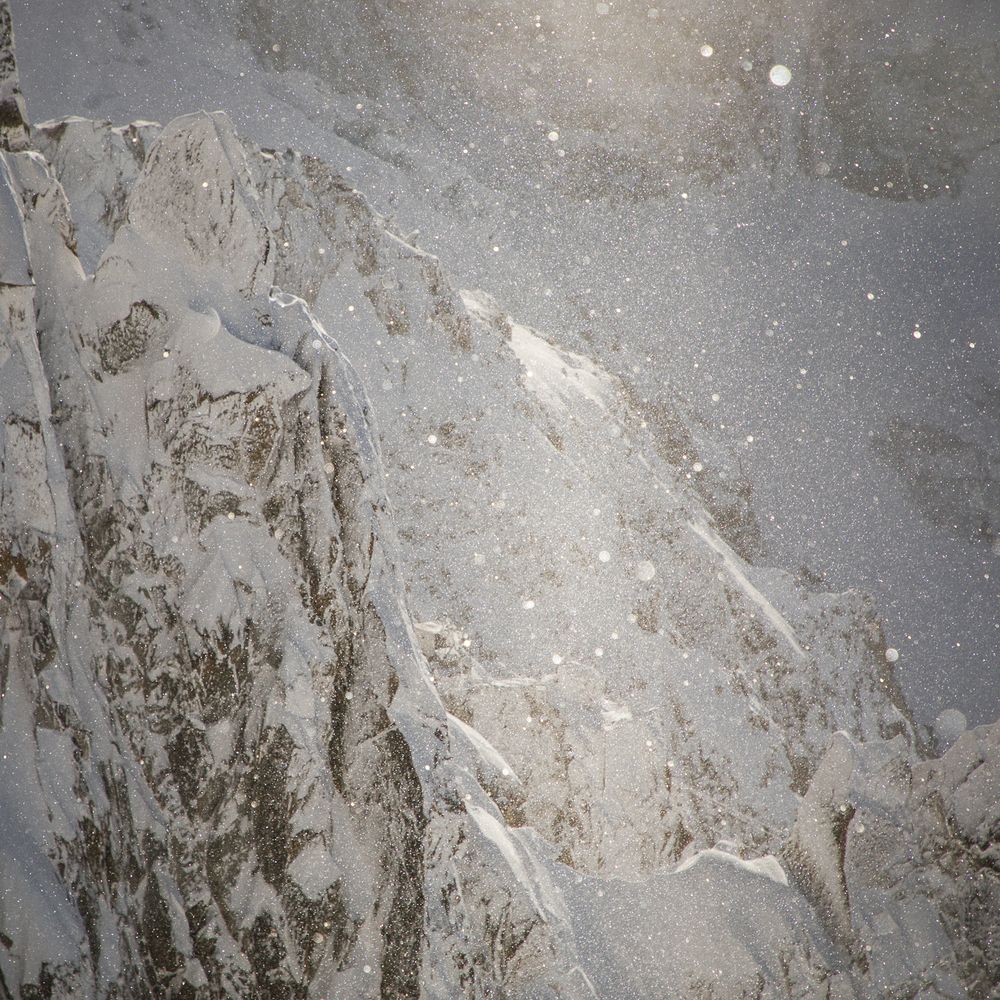 Rugged mountain surface with snow and ice formations creating natural patterns.
