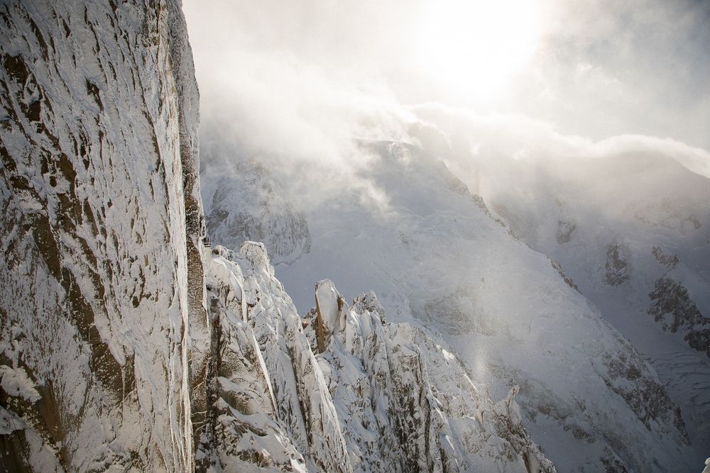Snow-capped mountain peaks with dramatic sunlight breaking through misty clouds.