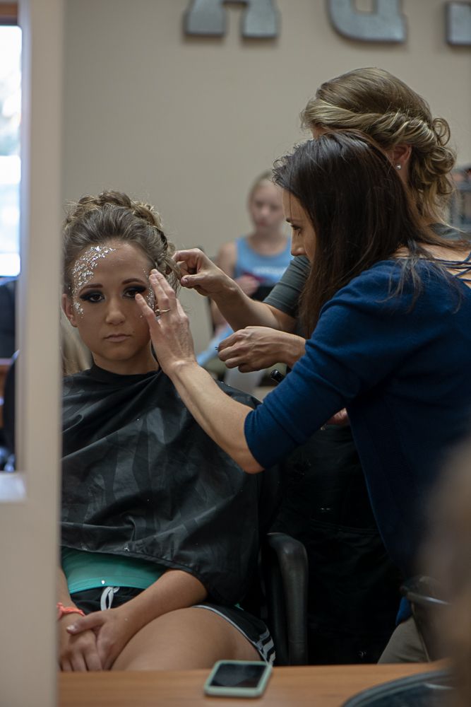Behind the scenes photo of a makeup artist applying glitter makeup to a client.