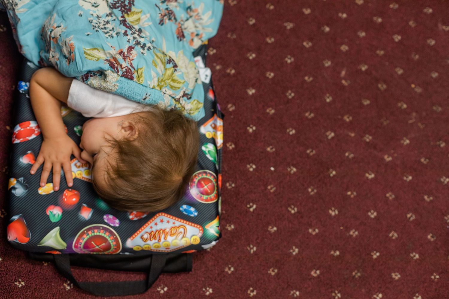 Overhead view of someone resting on a patterned pillow against red carpeting.