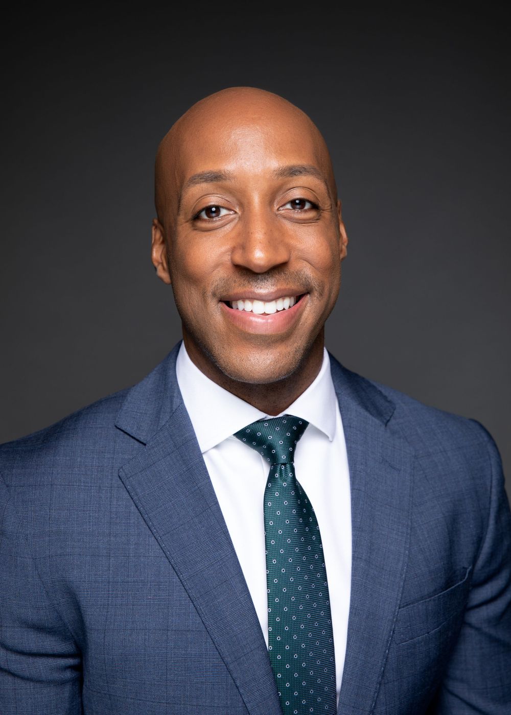 Professional headshot of Anchor for WUSA9 Lorenzo Hall in navy suit with polka dot tie smiling against dark background.