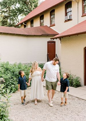 Family walking together outside brick building in casual summer clothing.