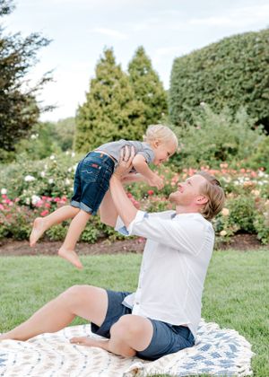 Playful interaction captured on a blanket in a flowering garden setting.