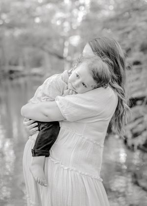 Heartwarming embrace between parent and child by peaceful lakeside.