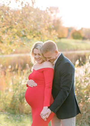Maternity photo of couple in formal wear during golden hour in nature.