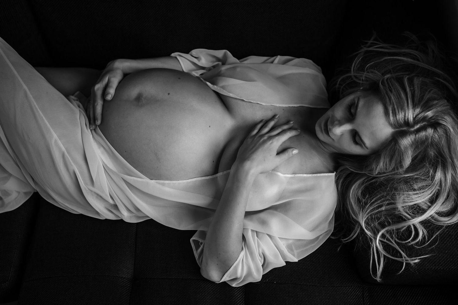 woman lies on back wearing sheer robe and displaying bump for pregnancy photographer london sarah stirk