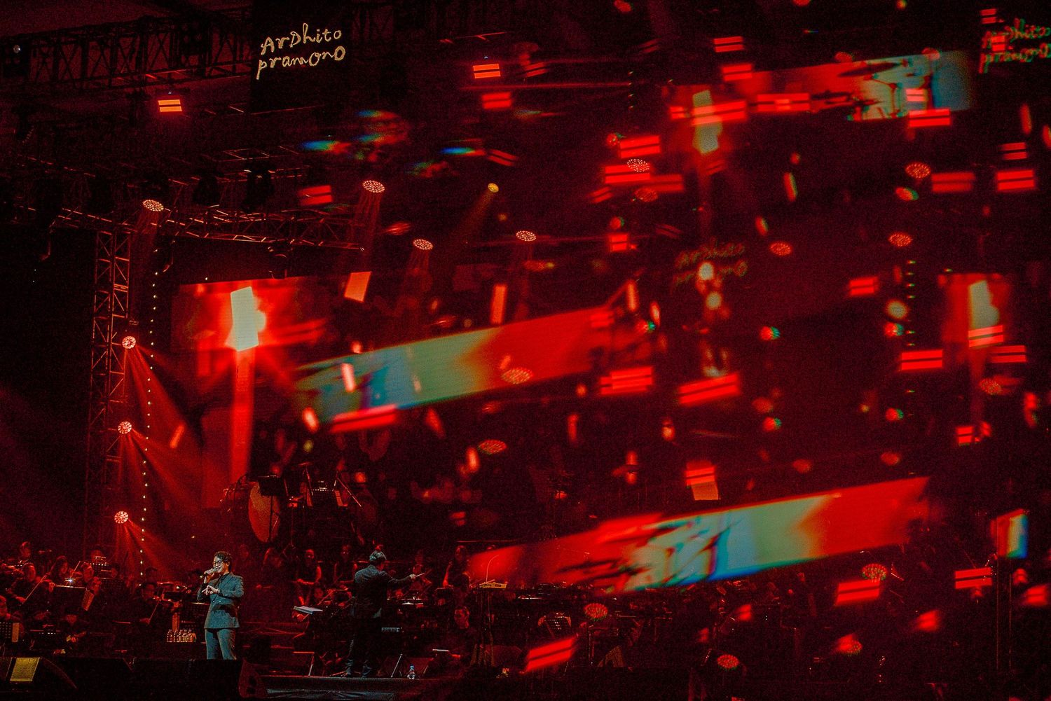 Concert stage bathed in red lighting with abstract visual effects creating a dramatic atmosphere.