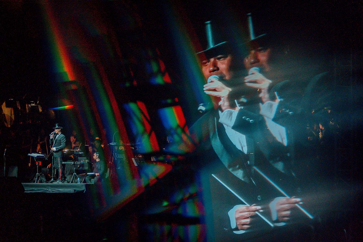 Concert performance with dramatic lighting effects and rainbow prisms on stage.