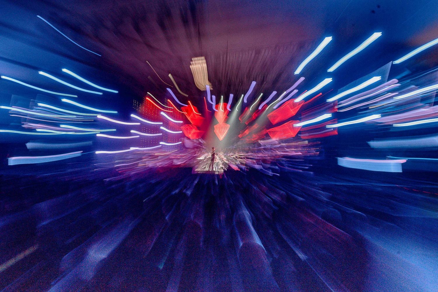 Abstract concert lighting effect with blue and red light trails creating a dynamic motion blur pattern.