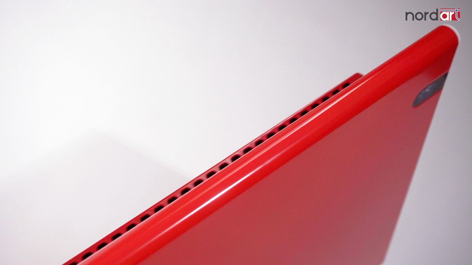 Close-up shot of a red laptop corner showing sleek design details.