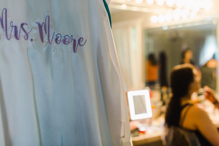 Custom Mrs. Moore text on clothing with beauty preparation scene in background.